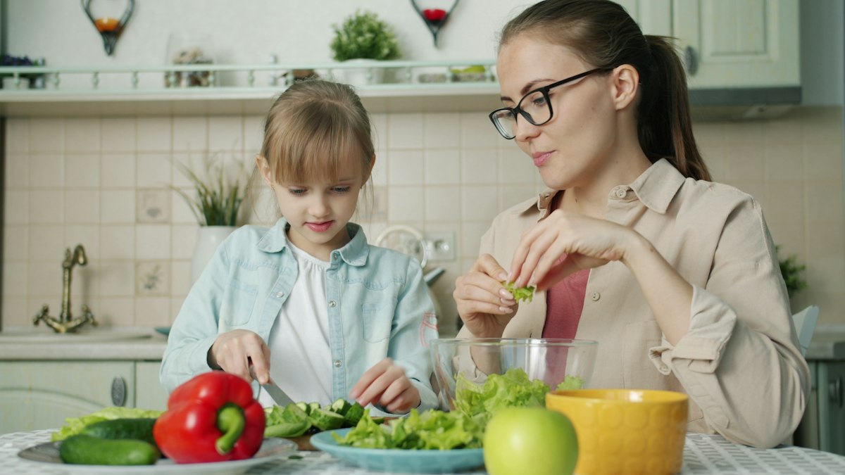 A child-friendly table set with fresh vegetables and extra virgin olive oil