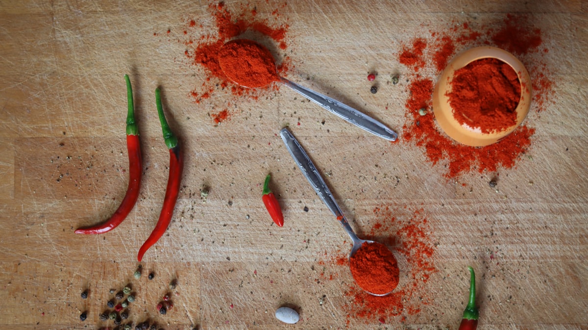 Spice infusion ingredients laid out — chili flakes, whole peppercorns, cumin seeds, and a bottle of olive oil