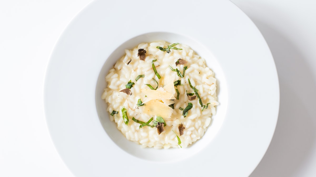 Olive oil being drizzled over risotto as a finishing step